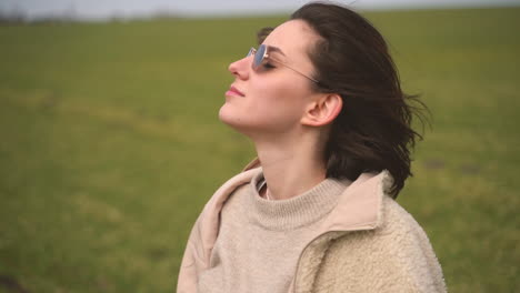 A-Young-Beautiful-Brunette-Girl-Puts-On-Sunglasses-In-A-Green-Meadow