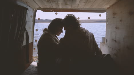 A-Young-Couple-In-Love-Put-Their-Heads-Together-In-The-Back-Of-A-Caravan-By-A-Lake-1