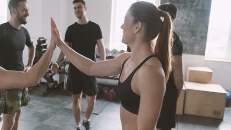 Strong-Young-Woman-Enters-Gym-And-High-Fives-Fellow-Students