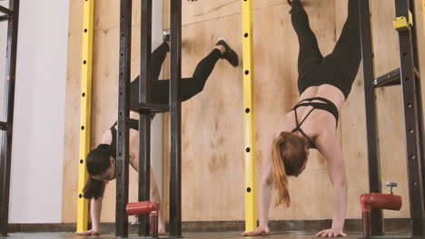 Two-Young-Athletic-Women-Doing-Abdominal-Exercises-And-Climbing-A-Wall-With-Their-Feet-In-The-Gym-1