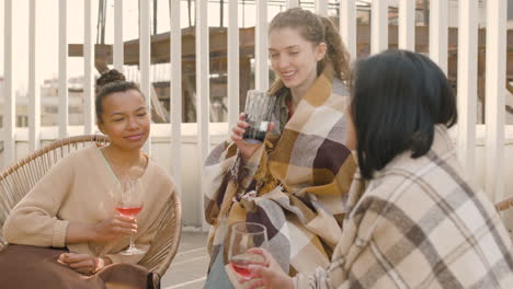 Eine-Nette-Multikulturelle-Gruppe-Von-Drei-Jungen-Mädchen,-Die-Sich-Unterhalten-Und-Wein-Trinken
