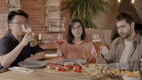 A-Group-Of-Three-Friends-Toast-With-Their-Glasses-At-A-Dinner-Party