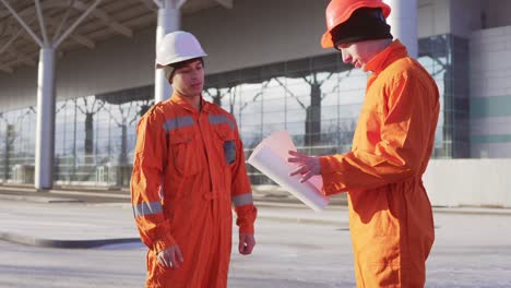 Projektleiter,-Der-Das-Bauobjekt-Mit-Bauarbeiter-In-Oranger-Uniform-Und-Helm-Untersucht