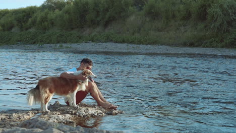 Young-Man-Pets-His-Dog-On-The-River-Bank