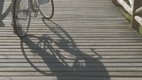 Shadow-Of-Cyclist-And-Bike-On-A-Sunny-Boardwalk