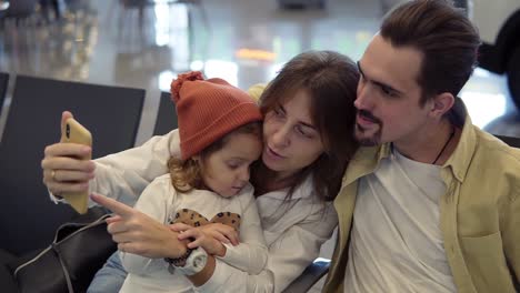 Young-Family-Doing-A-Selfie-With-Smart-Phone-While-Waiting-For-Airplane