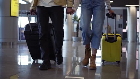 Cropped-Front-Footage-Of-Couple-Travelers-Are-Carrying-Their-Luggage-And-Holding-Hands