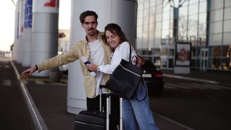 Stylish,-Young-Couple-With-Luggage-Standing-On-Airport-Parking-With-Their-Suitcases
