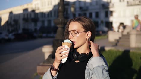 Young-Woman-In-Orange-Shirt-Enjoying-Soft-Vanilla-Ice-Cream-In-Waffle-Cone-Outdoors-In-Slow-Motion