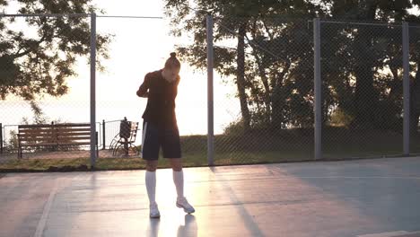 Sportliche-Junge-Frau-In-Hoodie-Und-Shorts,-Die-Sich-Morgens-Auf-Dem-Basketballplatz-Aufwärmen