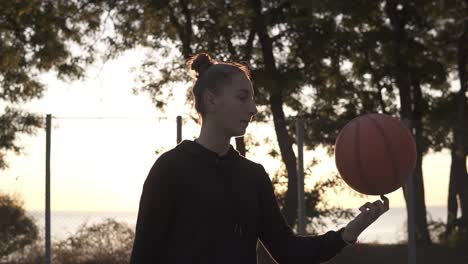 Beautiful-Girl-In-Black-Hoodie-Spinning-A-Basketball-On-Her-Finger-Outdoors