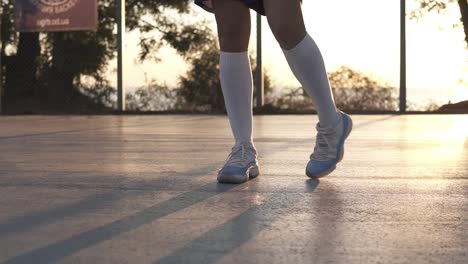 Young-Girl-Stretching-Her-Legs-In-White-Sneakers-And-White-Golf-Socks-On-The-Local-Basketball-Court