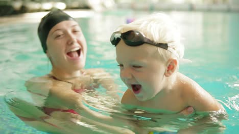 Happy-Little-Boy-Is-Swimming-In-The-Pool-Together-With-His-Mother