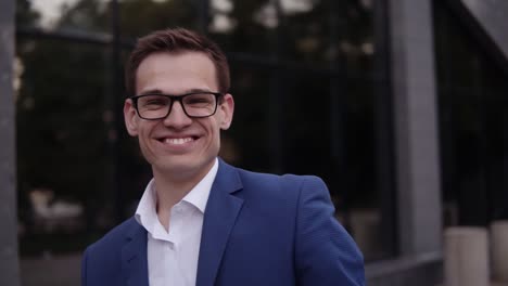 Upwards-Footage-Of-A-Young-Businessman-In-Elegant-Blue-Suit-And-Glasses-Standing-Outdoors