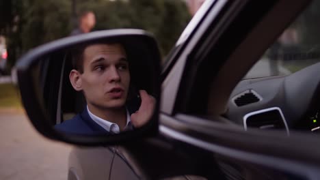 Handsome-Serious-Business-Man-In-Suit-And-White-Shirt-Talking-By-Mobile-Phone-In-The-Car