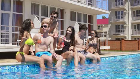 Glückliche-Gruppe-Junger-Freunde,-Die-Im-Sommer-Mit-Cocktails-Abhängen-Und-Am-Rand-Des-Pools-Plaudern-1