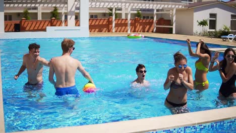 Group-Of-Young-Friends-Playing-Volley-Ball-In-The-Swimming-Pool