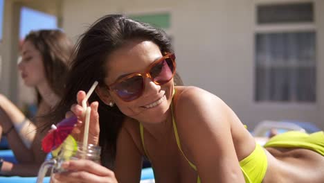 Beautiful-Young-Girl-In-Sunglasses-Drinking-Cocktails-With-Her-Female-Friends-Relaxing-By-The-Pool