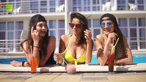 Beautiful-Young-Girls-In-Sunglasses-Drinking-Cocktails-Relaxing-By-The-Pool