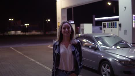 Portrait-Of-Romantic,-Smiling-Woman-At-The-Gas-Station-In-Caual,-The-Car-In-The-Background-Walks-And-Posing
