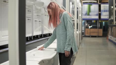 Blonde-Woman-Is-Choosing-A-New-Ceramic-Sink-In-A-Store