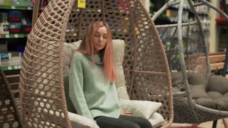 Woman-Choosing,-Sitting-In-A-Hanging-Chair-In-Hardware-Store