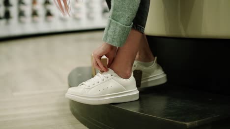 Woman-Is-Trying-New-White-Sneakers-In-Shoe-Store