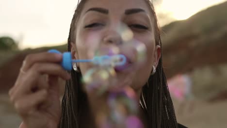 Young-Female-Hipster-With-Dreads-Cheerfully-Making-Soap-Bubbles-On-The-Beach-In-The-Evening-1