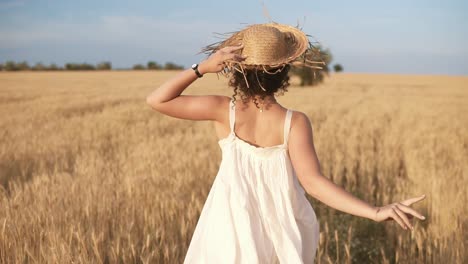 Tracking-Footage-Of-A-Beautiful-Girl-In-White-Summer-Dress-And-Straw-Hat-Running-Freely-By-Wheat-Field