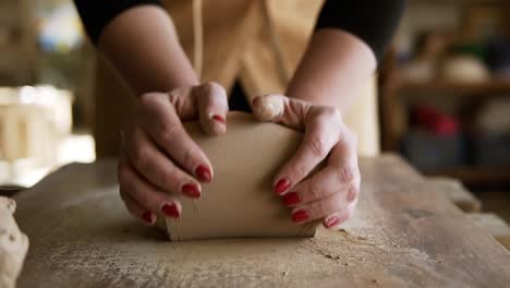 Close-Up-Footage-Of-Female-Hands-With-Beautiful-Red-Manicure-Holding-Clay-And-Kneading-It-On-A-Worktop