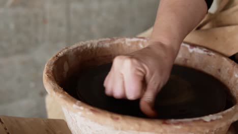 Close-Up-Footage-Of-Female-Hands-Wet-The-Empty-Potter-S-Wheel-Surface-Before-Work
