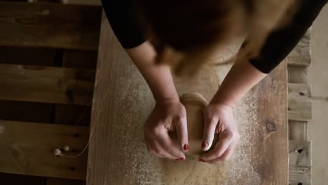 Top-Footage-Of-Female-Hands-With-Beautiful-Red-Manicure-Holding-Clay-And-Hardly-Kneading-It-On-A-Worktop