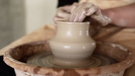 Close-Up-Of-Potter's-Dirty-Hands-Working-With-Wet-Clay-On-A-Pottery-Wheel-Making-A-Vase-In-A-Workshop
