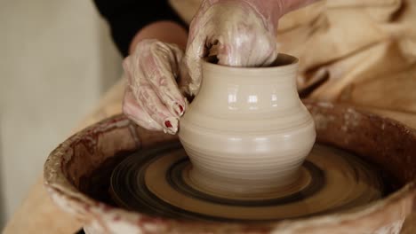 Female-Potter's-Hands-With-Red-Manicure-Working-With-Wet-Clay-On-A-Pottery-Wheel-Making-A-Clay-Product-In-A-Workshop