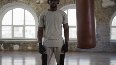 Boxer-Is-Looking-At-Camera-While-Standing-Near-The-Punching-Bag
