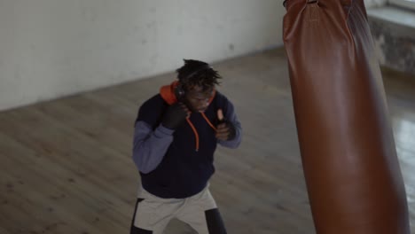 Boxer-Punching-The-Heavy-Bag-In-The-Gym,-High-Angle-View