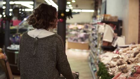 Seltene-Ansicht-Einer-Frau,-Die-Einen-Einkaufswagen-Durch-Die-Lebensmittelabteilung-Im-Supermarkt-Fährt-Und-Sich-Umsieht-Und-Eine-Tasche-Mit-Kartoffeln-Auswählt