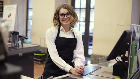 Woman-In-Black-Apron-As-A-Cashier-At-The-Cash-Register-In-The-Supermarket-Or-Discounter
