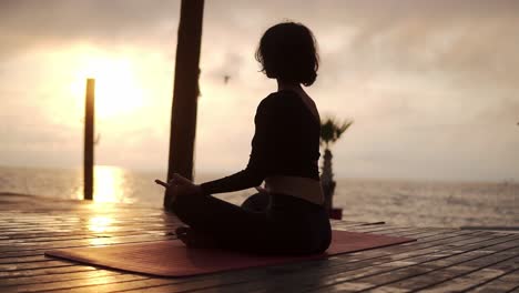Yogi-Mädchen-Sitzt-Im-Sommer-Bei-Sonnenuntergang-In-Lotus-Pose-Vor-Dem-Meer-Und-Meditiert-über-Möwen,-Die-Am-Himmel-Herumfliegen