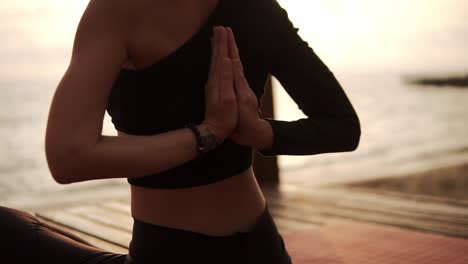 Frau,-Die-Yoga-Praktiziert-Und-Wirbelsäule-Und-Hände-Dehnt,-Die-Auf-Einer-Matte-Am-Seesteg-Sitzen,-Verbindet-Sich-Mit-Den-Händen-Hinter-Ihrem-Rücken
