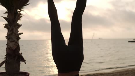 Woman-Standing-On-Head-In-Yoga-Pose-Salamba-Shirshasana-Outdoor,-Practicing-Yoga-Asana-On-Summer-Terrace-In-Front-The-Sea