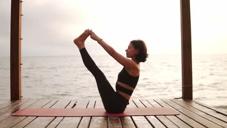 Mujer-Practicando-Yoga-Sentada-En-Una-Alfombra-En-El-Muelle-Marino-Realizando-Ubhaya-Padangusthasana