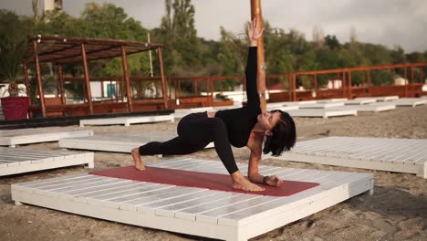 Mujer-Practicando-Yoga-En-La-Alfombra-En-La-Playa-Haciendo-Yoga-O-Estirando-Las-Piernas,-Realizando-Una-Pose-De-ángulo-Lateral-Extendido
