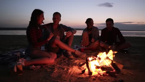 Two-Young-Couples-Are-Sitting-On-The-Beach-Near-The-Bonfire