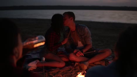 Pretty-Couple-Feeding-Each-Other-With-Marshmallow-On-Stick,-Kissing-In-Front-Of-Bonfire