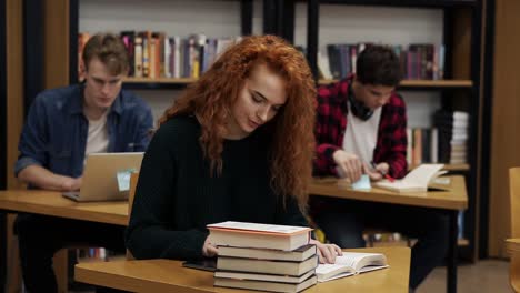 Portrait-Of-A-Young-Red-Headed-Curly-Female-Student-Working-On-Her-Thesis-Or-Preparing-For-Exam