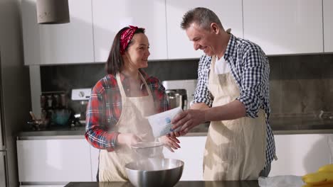 The-Couple-Sifting-Flour-To-Make-Bread-In-Kitchen