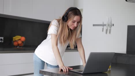 Mujer-Que-Pasa-Tiempo-Con-Una-Laptop-Usando-Audífonos-En-Casa