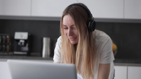 Woman-Using-Laptop-Wearing-Headphones-At-Home