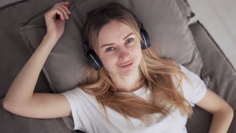 Woman-Relaxing-And-Enjoying-Music-In-Headphones-On-Couch
